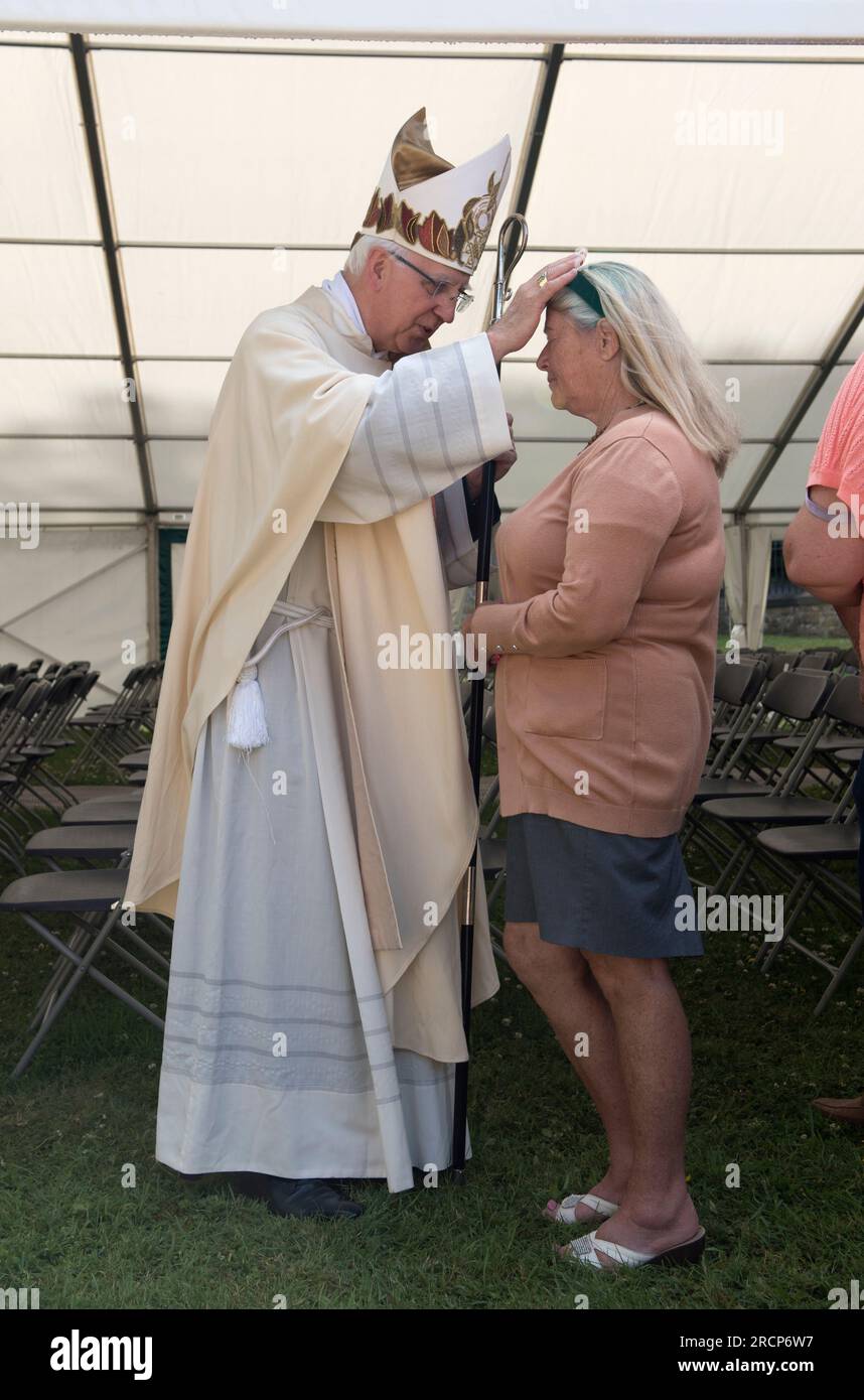 Posa delle mani UK. Vescovo cattolico di Wrexham, il reverendo Peter M Brignall. Egli è benedetto - a mani nude - dopo un servizio ecclesiastico all'aperto in un tendone per un devoto viaggiatore cattolico irlandese al pellegrinaggio del giorno della festa di Saint Winefride. Holywell, Flintshire, Galles, 25 giugno 2023. 2000 HOMER SYKES Foto Stock