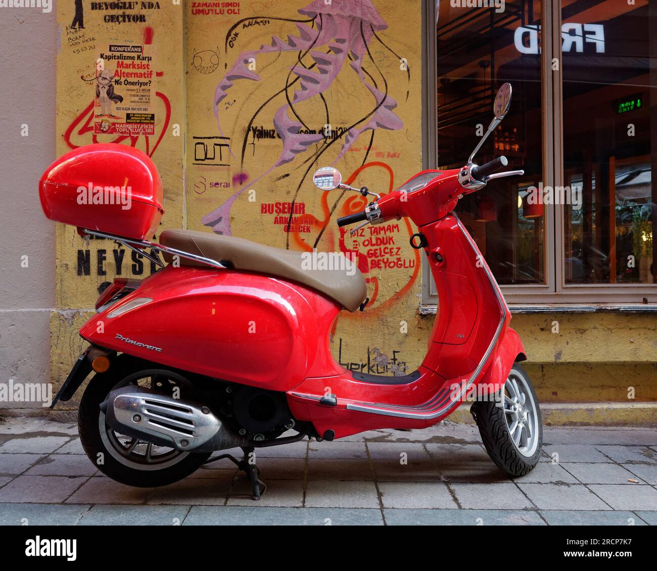 Red Scooter in una strada con un muro giallo a Istanbul, in Turchia Foto Stock