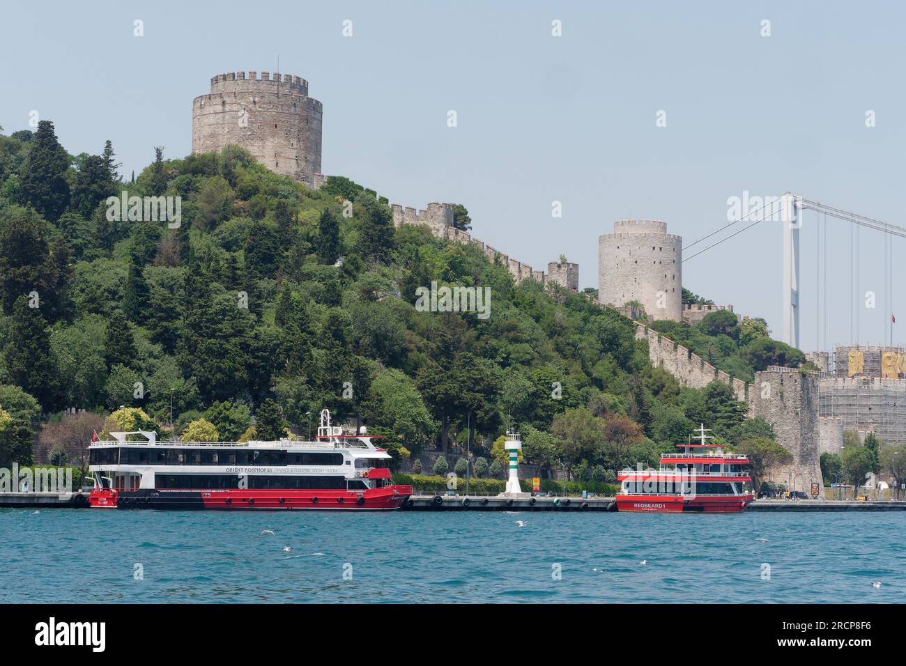 Fortezza di Rumeli su una collina con traghetti passeggeri sul lungomare del Bosforo e sul ponte Fatih Sultan Mehmet, Istanbul, Turchia Foto Stock