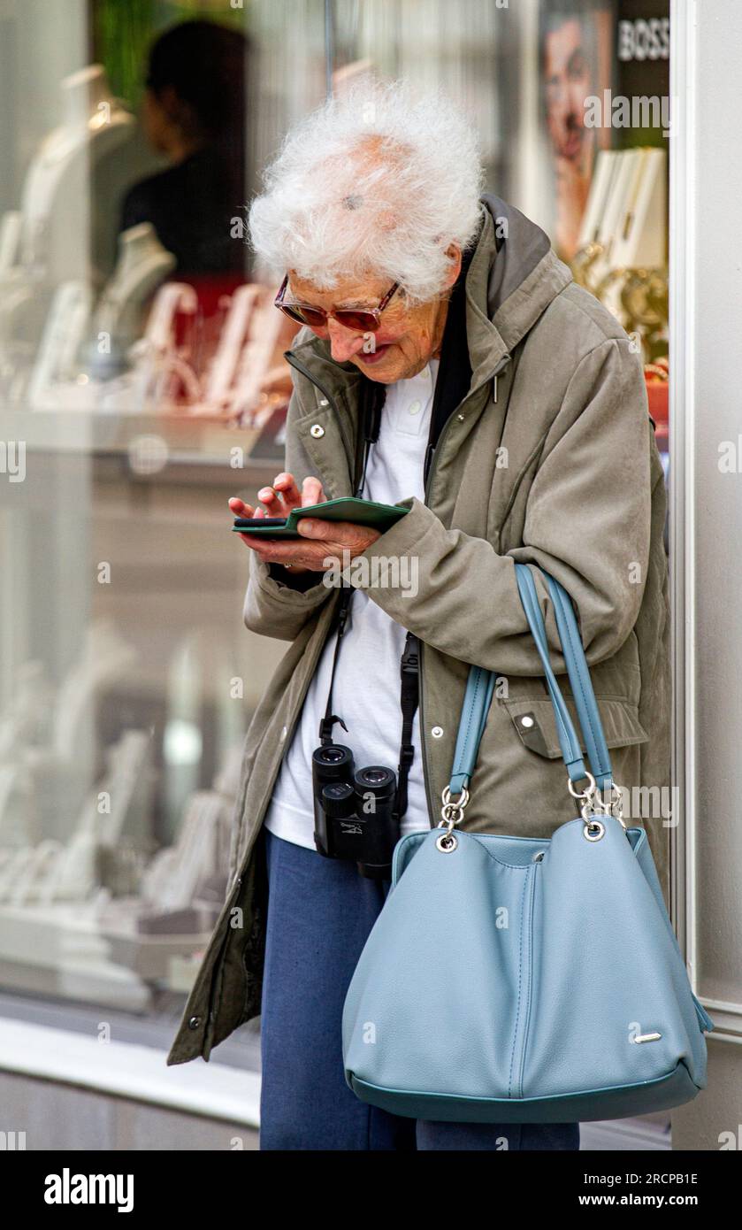 Dundee, Tayside, Scozia, Regno Unito. 16 luglio 2023. Tempo nel Regno Unito: Domenica mattina di luglio a Tayside, in Scozia, era luminosa e umida, con temperature che raggiungevano i 20°C. Le donne alla moda locali trascorrono la giornata nel centro di Dundee, godendosi il tempo del fine settimana mentre comunicano con i loro telefoni cellulari e i-phone. Crediti: Dundee Photographics/Alamy Live News Foto Stock