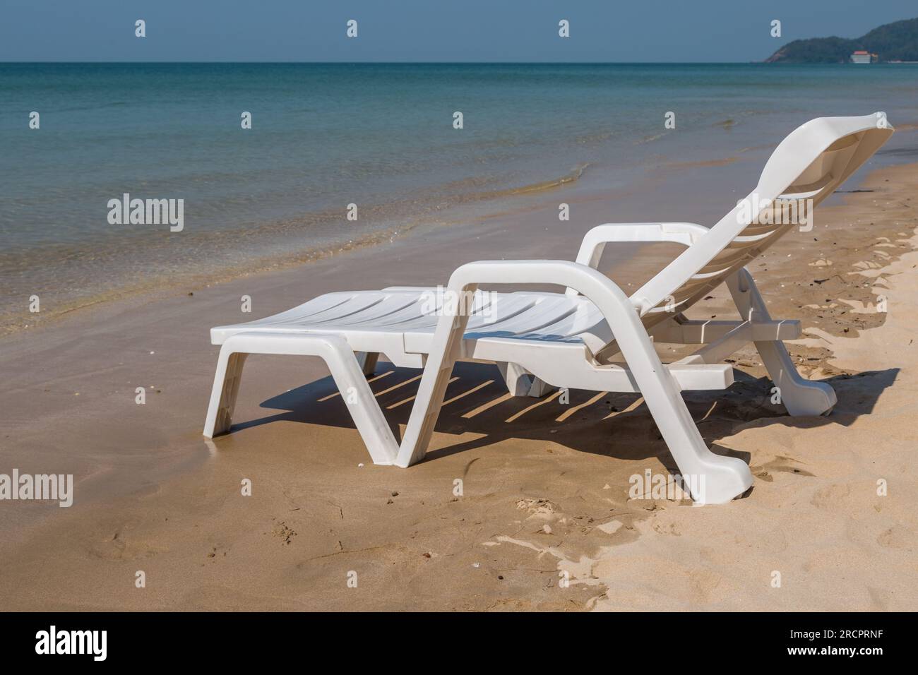 Sedia da spiaggia a costa soleggiata sullo sfondo della spiaggia Foto Stock