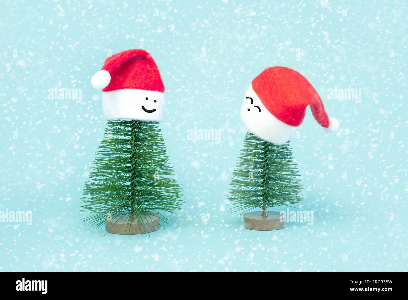 Due piccoli alberi di Natale in rosso Babbo Natale. Decorazione di abete artificiale. Bella imitazione di un piccolo albero di Natale, con Santa Cap su blu b Foto Stock