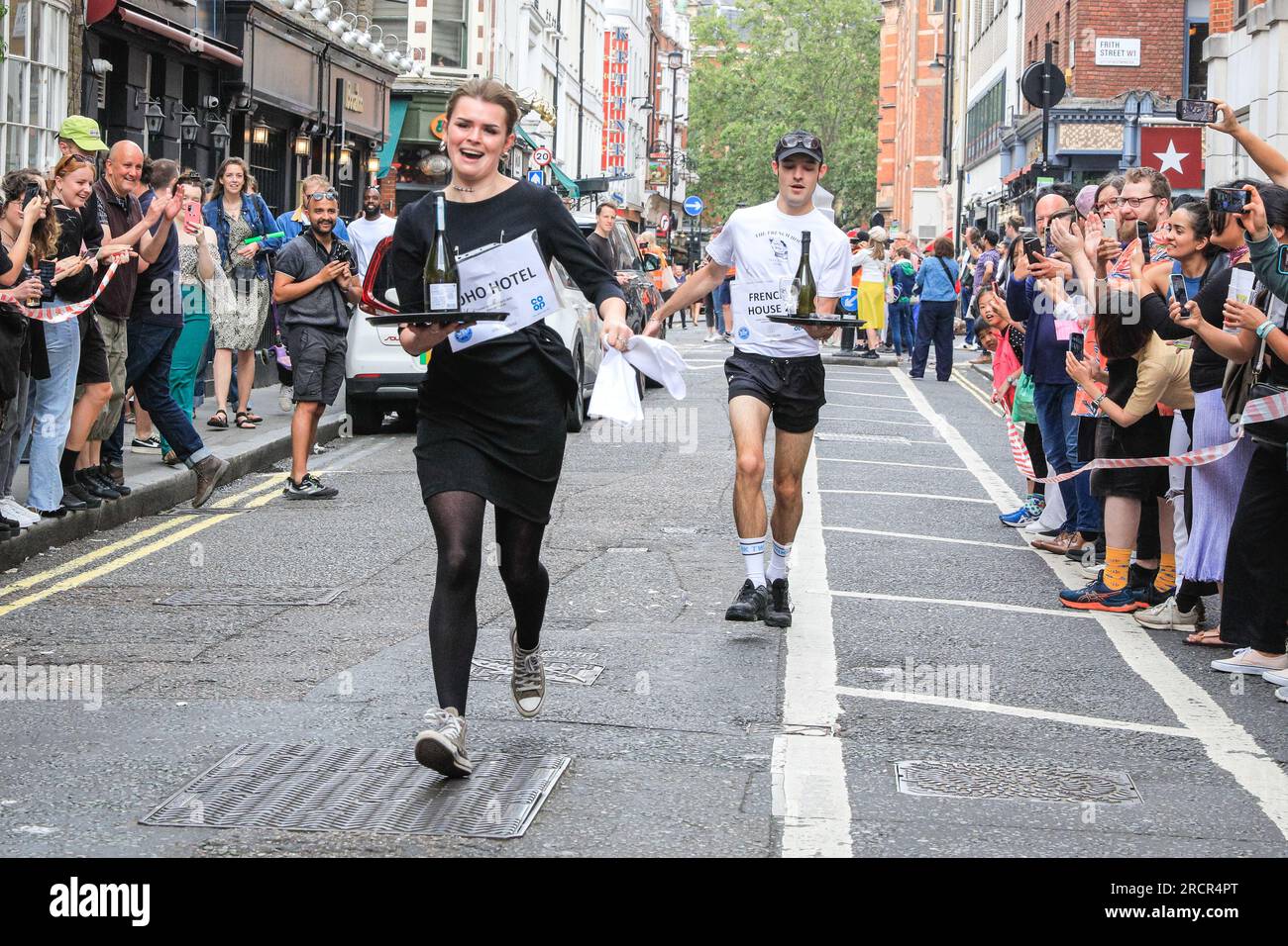 Londra, Regno Unito. 16 luglio 2023. I camerieri stanno arrivando al traguardo. L'annuale Soho Waiters Race si fa strada a Soho. La lunga tradizione, che risale al 1950, vede i camerieri di molti ristoranti e bar nelle vicinanze correre per le strade di Soho con un vassoio, un tovagliolo, una mezza bottiglia di champagne e un bicchiere di champagne. I camerieri poi festeggiano dopo. Crediti: Imageplotter/Alamy Live News Foto Stock