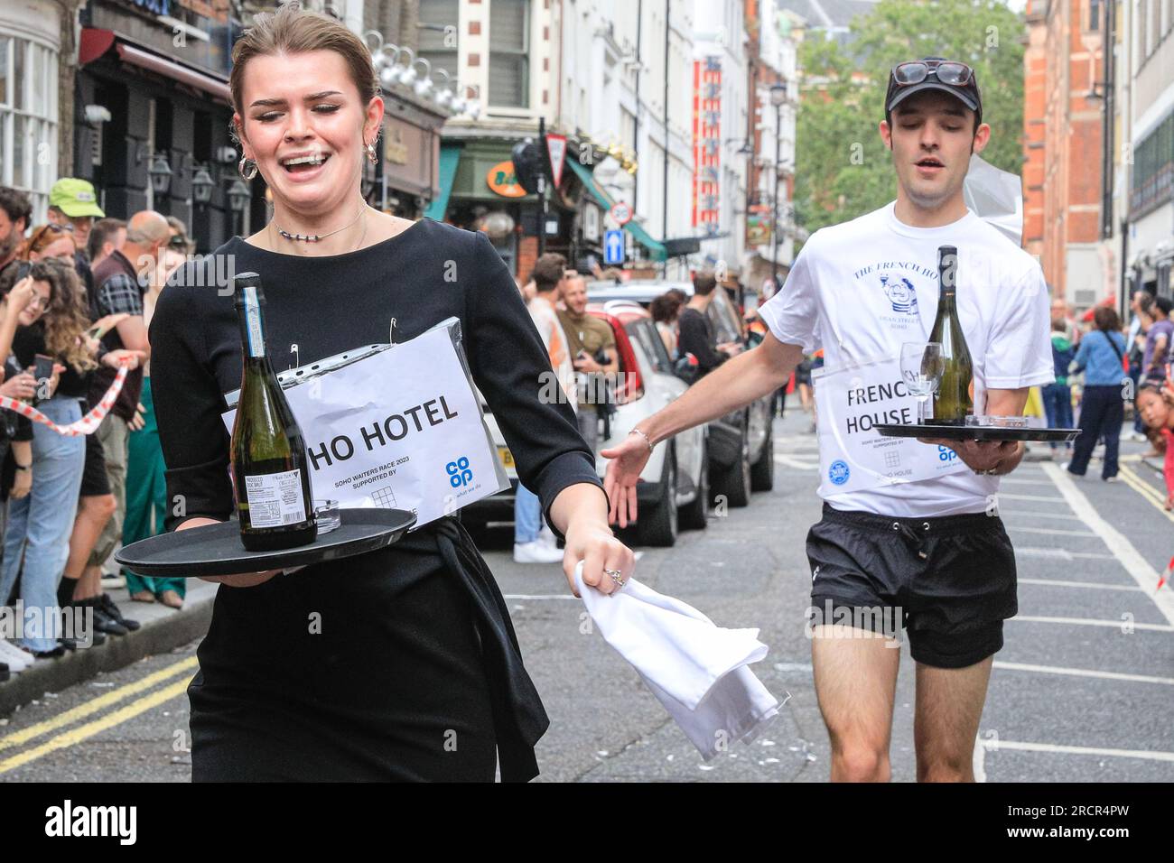 Londra, Regno Unito. 16 luglio 2023. I camerieri stanno arrivando al traguardo. L'annuale Soho Waiters Race si fa strada a Soho. La lunga tradizione, che risale al 1950, vede i camerieri di molti ristoranti e bar nelle vicinanze correre per le strade di Soho con un vassoio, un tovagliolo, una mezza bottiglia di champagne e un bicchiere di champagne. I camerieri poi festeggiano dopo. Crediti: Imageplotter/Alamy Live News Foto Stock