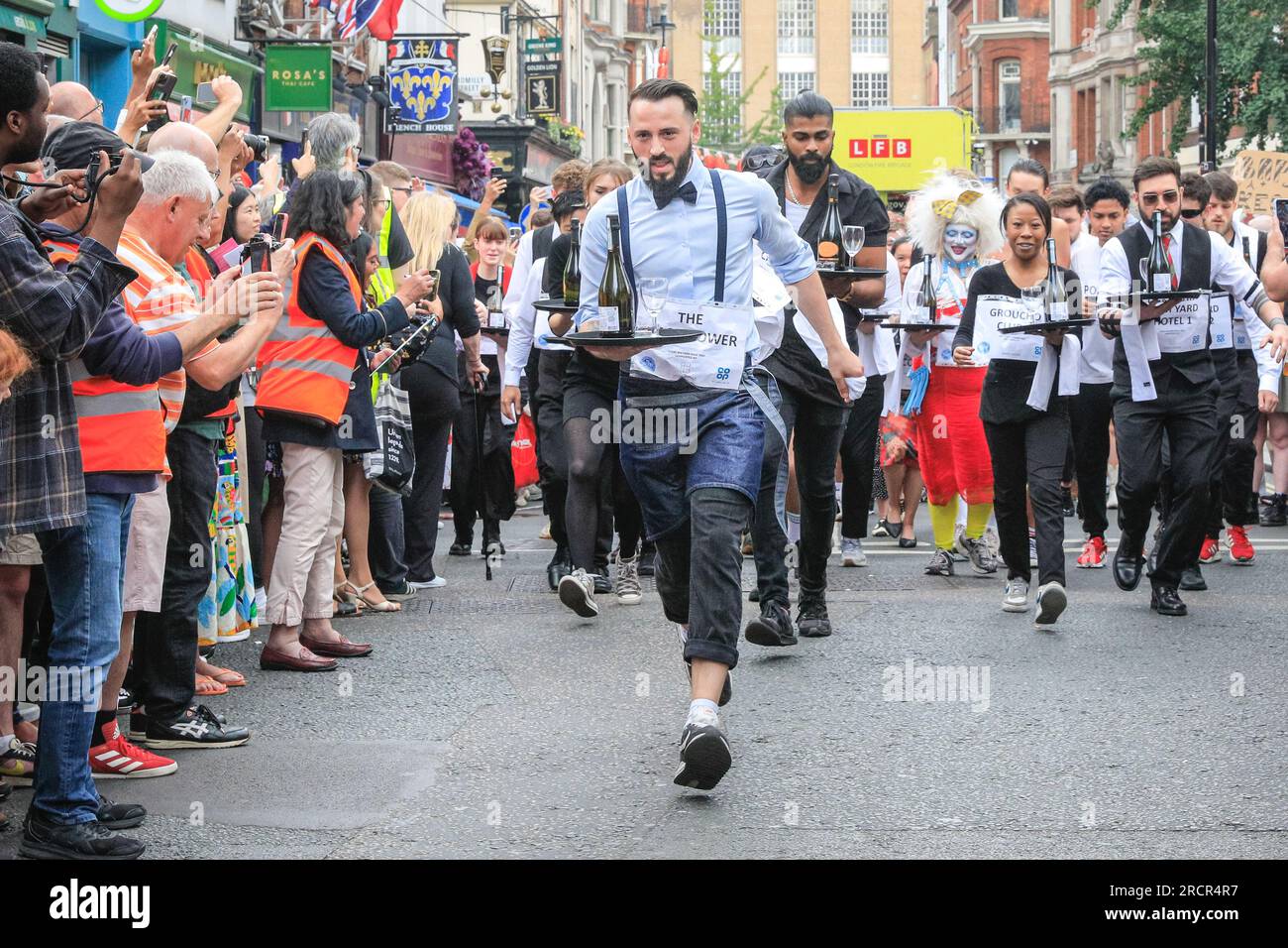 Londra, Regno Unito. 16 luglio 2023. I concorrenti all'inizio della gara. L'annuale Soho Waiters Race si fa strada a Soho. La lunga tradizione, che risale al 1950, vede i camerieri di molti ristoranti e bar nelle vicinanze correre per le strade di Soho con un vassoio, un tovagliolo, una mezza bottiglia di champagne e un bicchiere di champagne. I camerieri poi festeggiano dopo. Crediti: Imageplotter/Alamy Live News Foto Stock