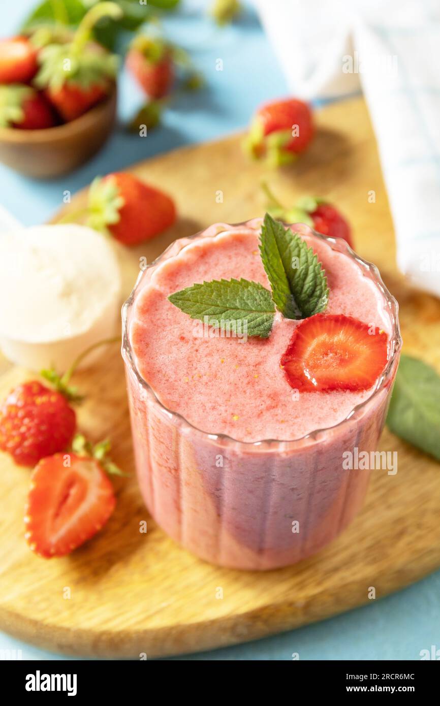 Latte fresco, bevande alla fragola su tavola di legno su uno sfondo di pietra, frullato proteico con frutti di bosco freschi. Foto Stock