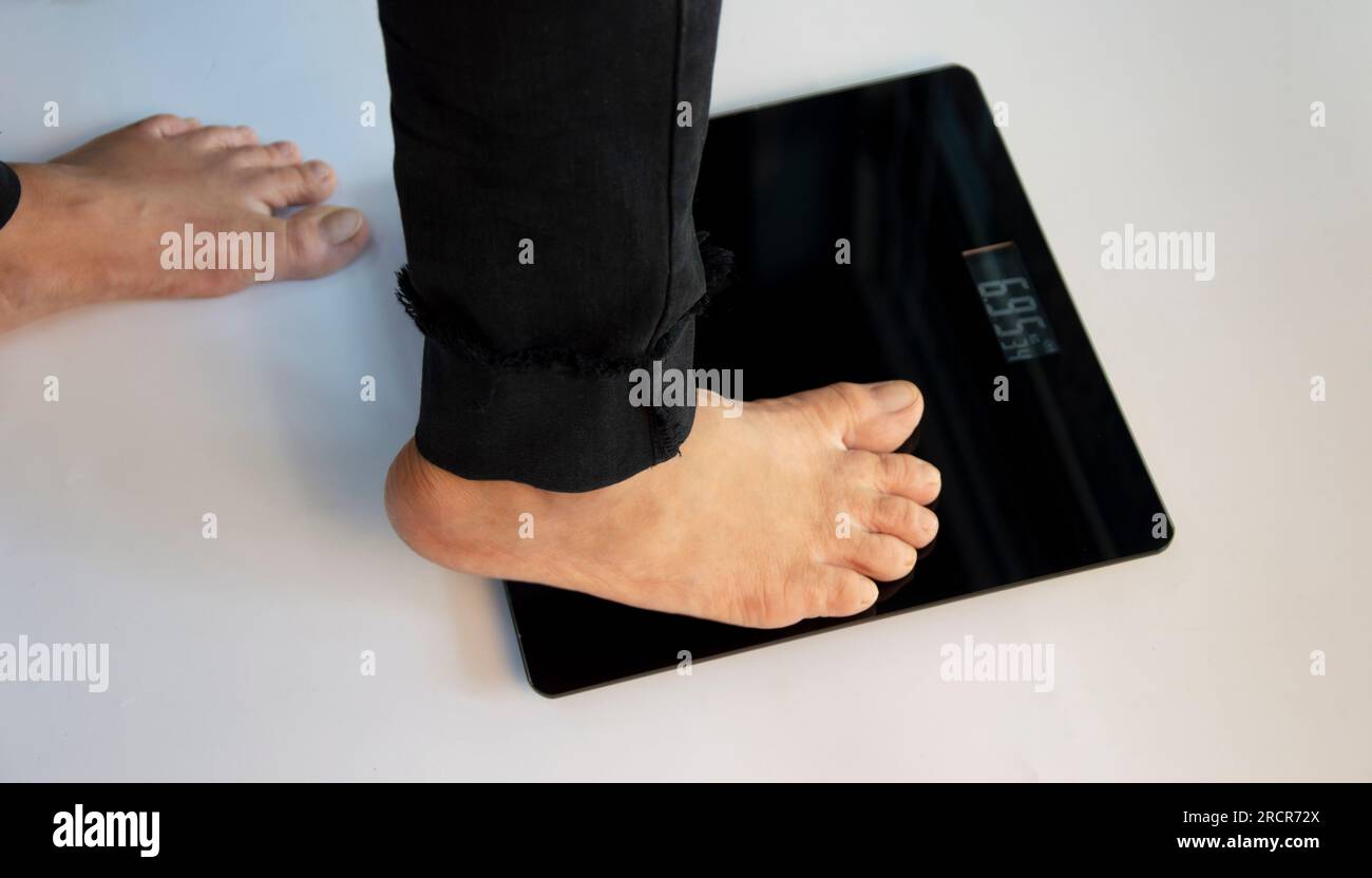 In piedi sulle bilance per interni c'è spazio per il testo. Il problema di essere sovrappeso o sottopeso Foto Stock
