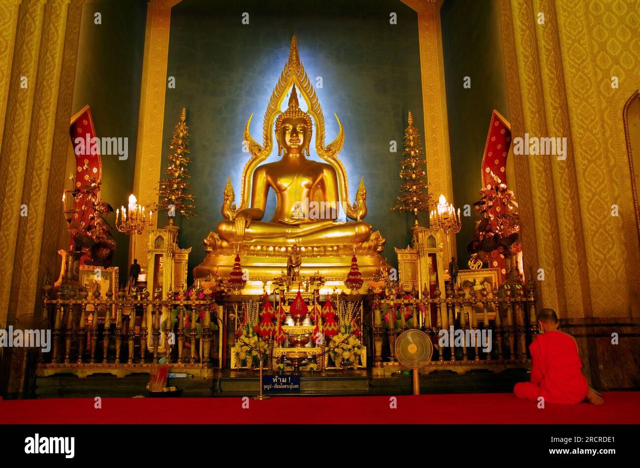 Illuminante statua dorata del Buddha con sfondo blu Foto Stock