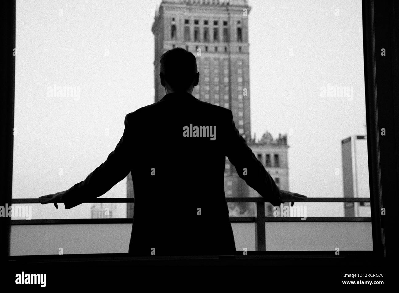 Silhouette di uomo sul balcone che si affaccia sul grattacielo. Foto Stock