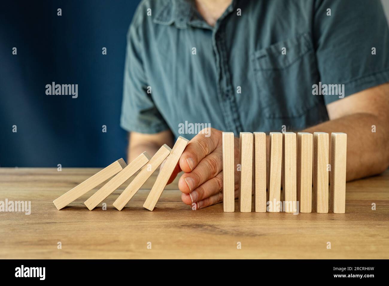 la mano di un manager efficiente smette di cadere da blocchi di legno, pianificazione e concetto strategico, interruzione delle attività aziendali, ristrutturazione aziendale, azioni necessarie Foto Stock