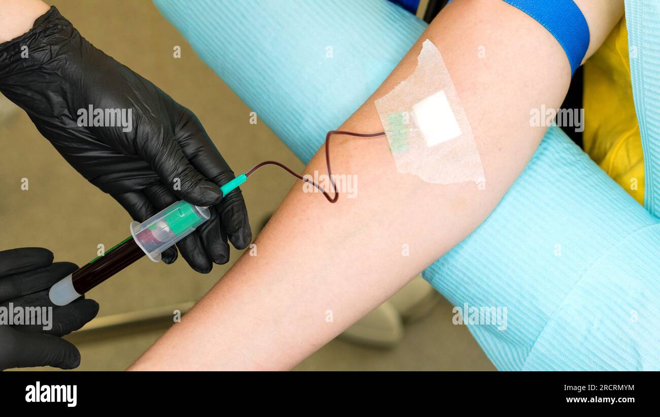 Infermiere che inietta il paziente con la siringa per prelevare il campione di sangue. Il tecnico di laboratorio preleva i campioni di sangue utilizzando il supporto per provette del laboratorio clinico Foto Stock
