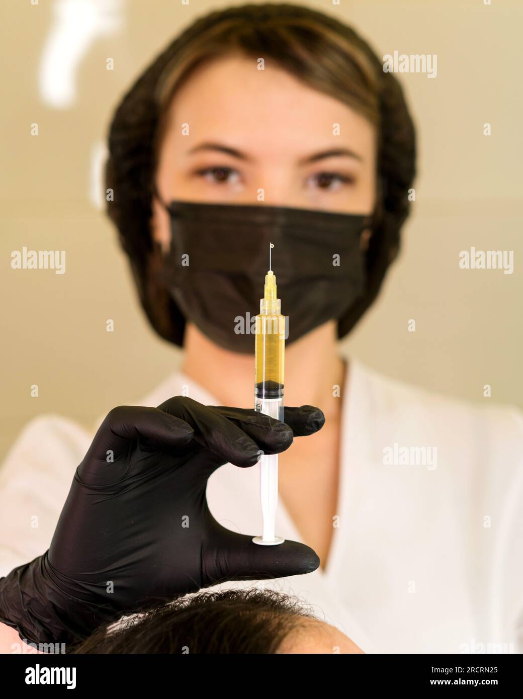 Siringa in mano tricologa per terapia PRP con plasma ricco di piastrine ematiche estratto dalla centrifuga medica per il trattamento del sollevamento del plasma Foto Stock