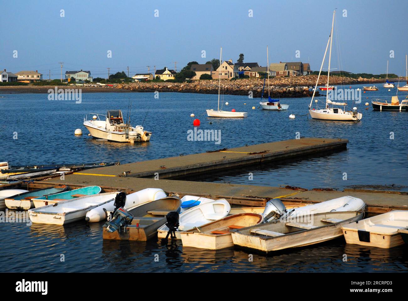 Piccoli gommoni fiancheggiano un molo in un porto calmo in una soleggiata giornata estiva Foto Stock