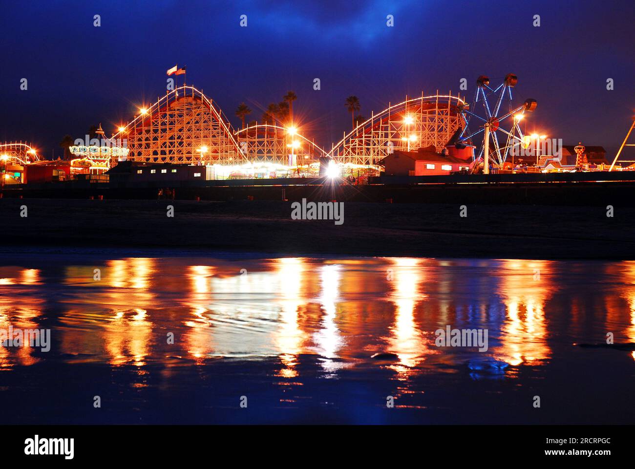 L'area dei divertimenti di Santa Cruz California è illuminata al crepuscolo e si riflette nell'acqua vicino al parco Foto Stock