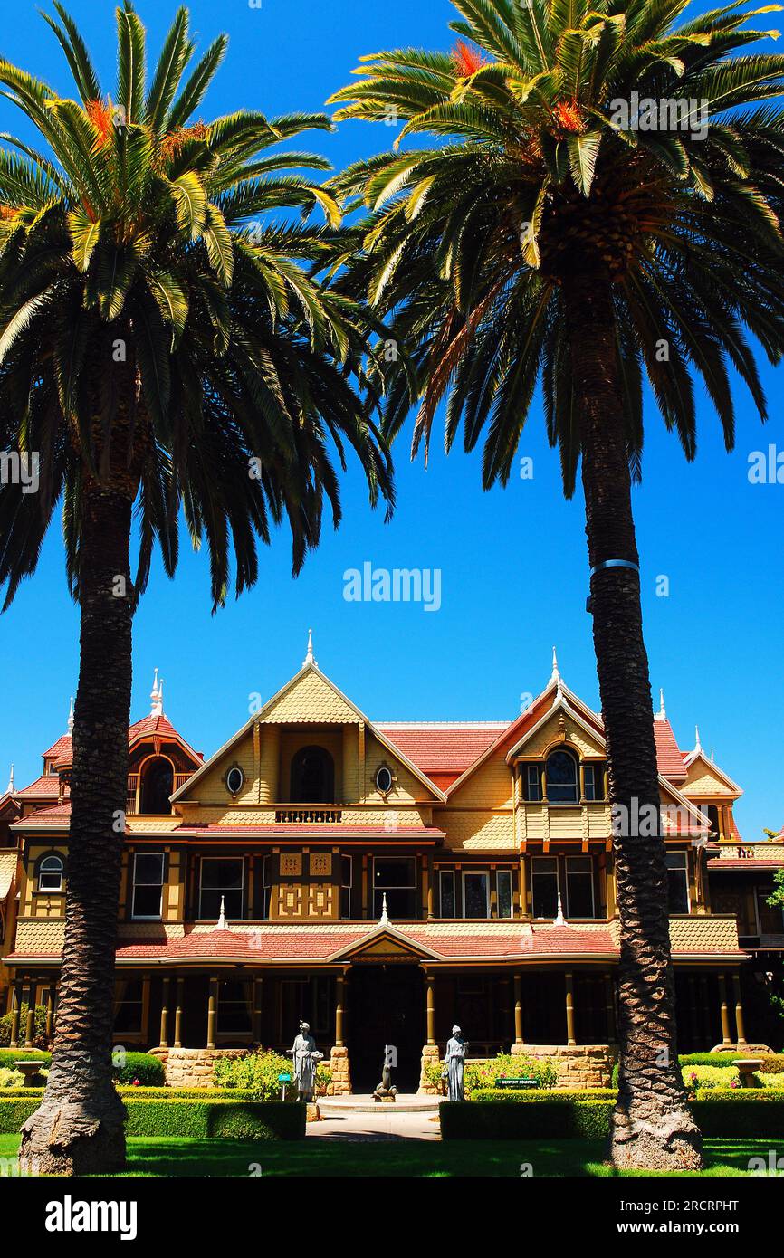 Due palme incorniciano la Winchester Mystery House, storica dimora infestata da fantasmi a San Jose, California Foto Stock