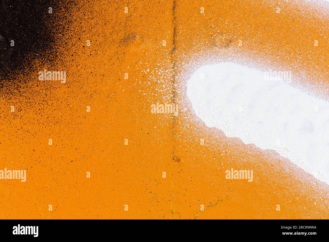 Primo piano macro di uno spray da parete verniciato con arancio, nero e bianco con schizzi. Sfondo graffiti astratto con texture e schizzi con spazio per la copia. Foto Stock