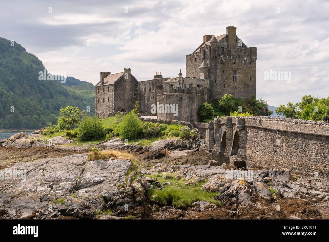 Sole sul castello di Eilean Donan e sulla strada sopraelevata per l'isola sul Loch Duich a Low Tide in estate Foto Stock