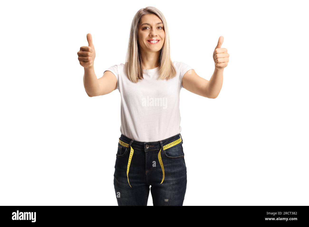 Giovane donna slim in jeans con un metro a nastro intorno alla vita pollice con gesti in alto isolato su sfondo bianco Foto Stock