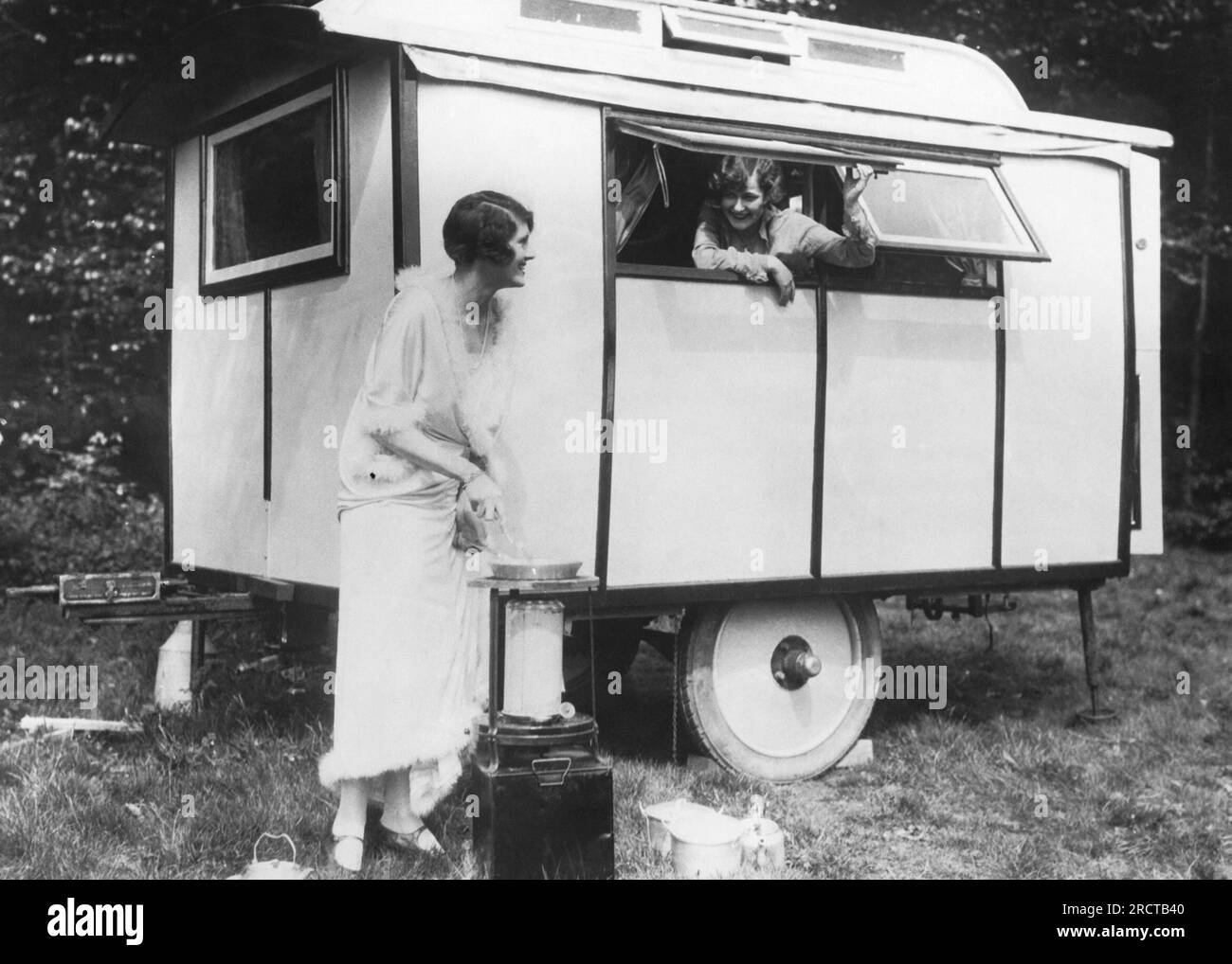 Stati Uniti: c. 1925 due donne che si accamparono in un rimorchio, con una che prepara un pasto fuori. Foto Stock
