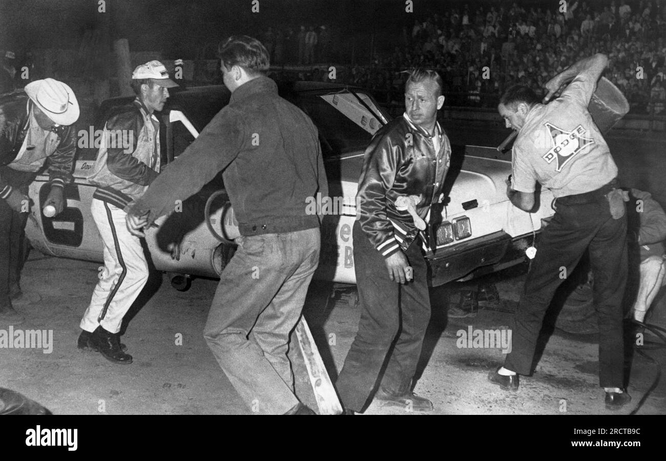 South Carolina: 1964 Cotton Owens, davanti alla macchina fotografica, asso meccanico di gara per i Carolina Dealers, si affrettano a duellare duramente in una gara notturna quando il pilota David Pearson fa un pit stop. Foto Stock