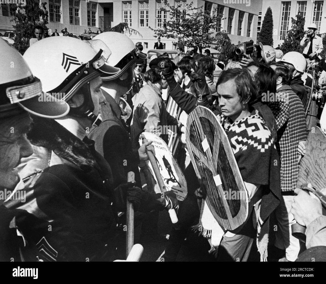 Oakland, California: 23 aprile 1968 Un manifestante con uno scudo per il segno di pace affronta una linea di polizia in marcia antisommossa. Foto Stock