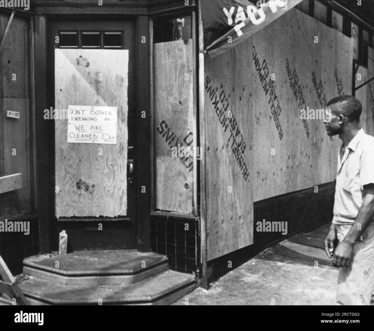 Philadelphia, Pennsylvania: 30 agosto 1964 Un uomo cammina davanti a un negozio a North Philadelphia dopo due notti di disordini e saccheggi. Il cartello dice: "Non preoccuparti di entrare, siamo ripuliti". Foto Stock