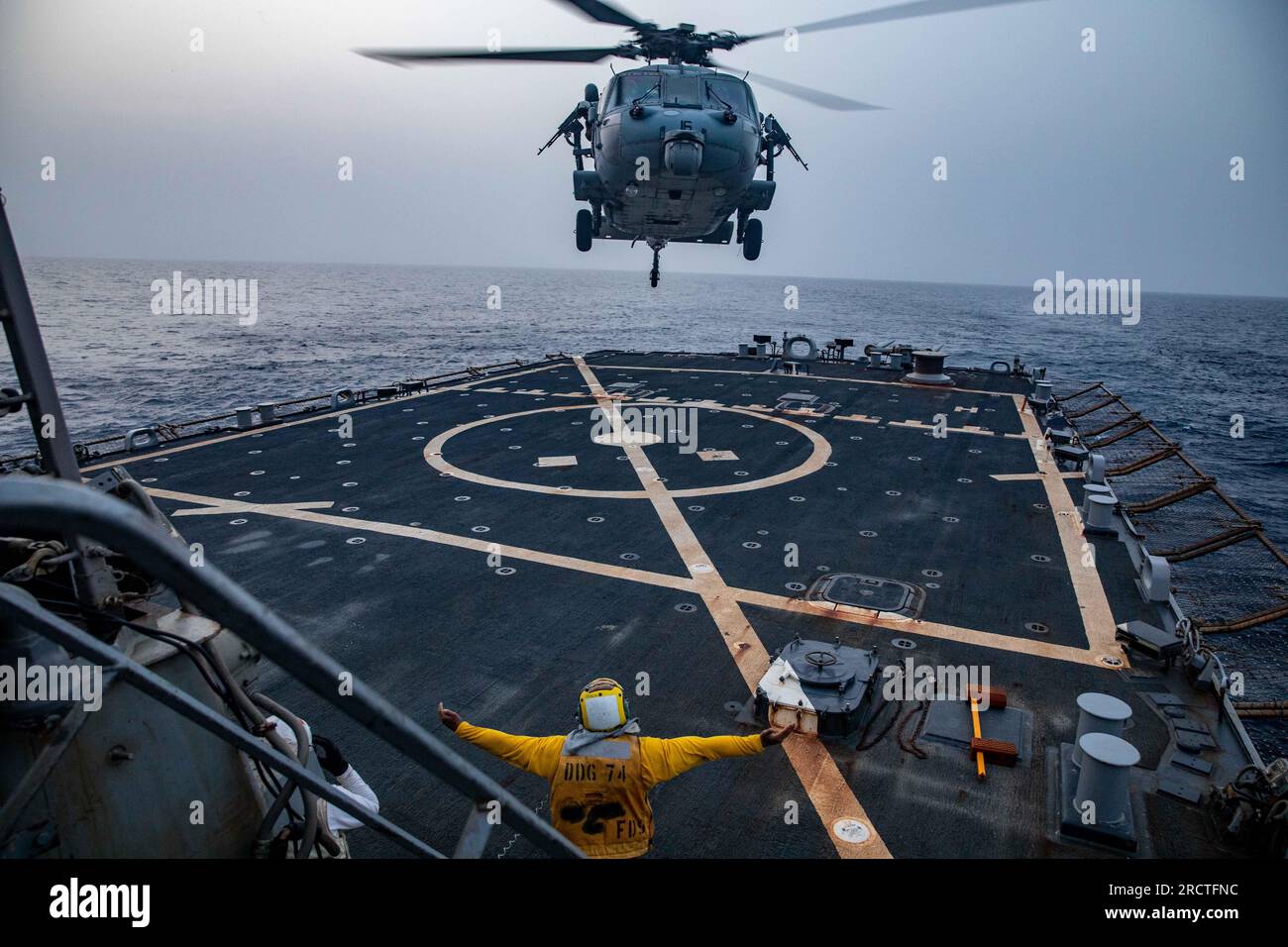 GULF OF OMAN (14 luglio 2023) il Boatswain's Mate 2nd Class Asahiah Grimes, assegnato al cacciatorpediniere missilistico guidato USS McFaul (DDG 74), dirige un elicottero MH-60S durante un'evoluzione dei quartieri di volo nel Golfo dell'Oman, 14 luglio 2023. McFaul è schierato nell'area operativa della 5th Fleet degli Stati Uniti per contribuire a garantire la sicurezza marittima e la stabilità nella regione del Medio Oriente. (STATI UNITI Foto di Juel Foster, specialista di comunicazione di massa di seconda classe) Foto Stock