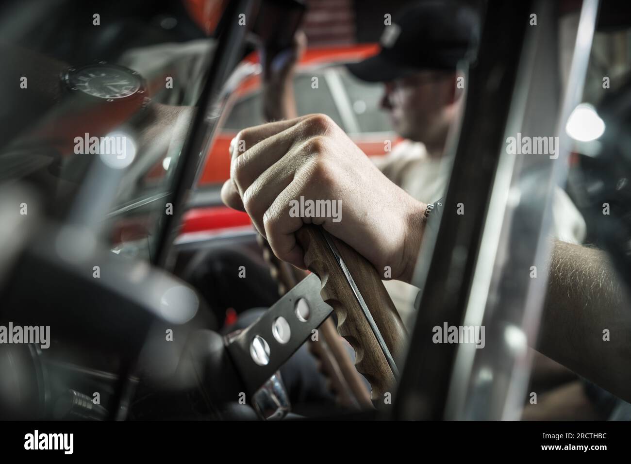 Due ragazzi dentro un'auto classica. Primo piano della mano sul volante Foto Stock