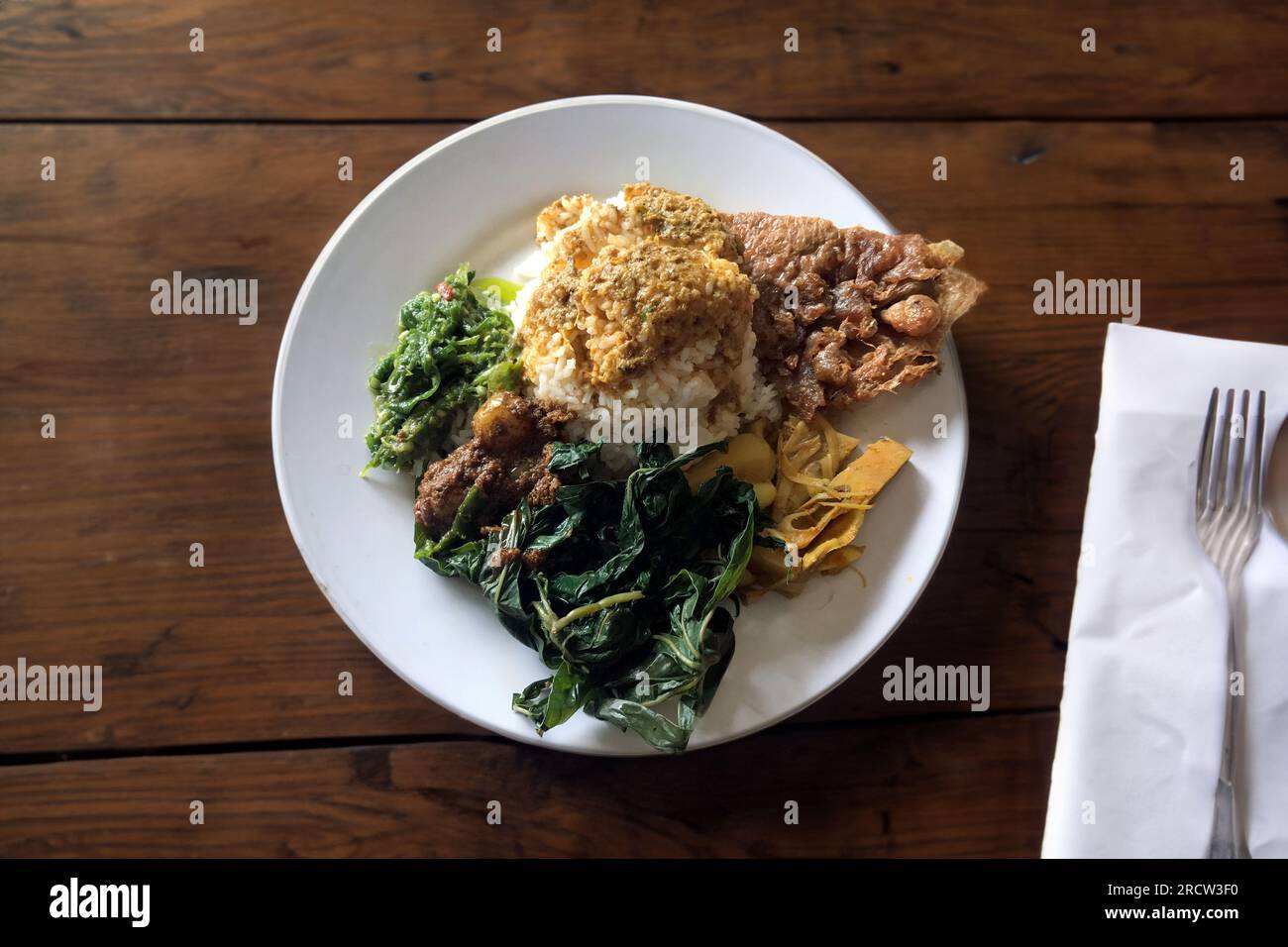 Nasi Padang composto da riso bianco, rendang, uovo, verdure in un piatto bianco. Cibo tradizionale indonesiano. Rendang Padang Foto Stock