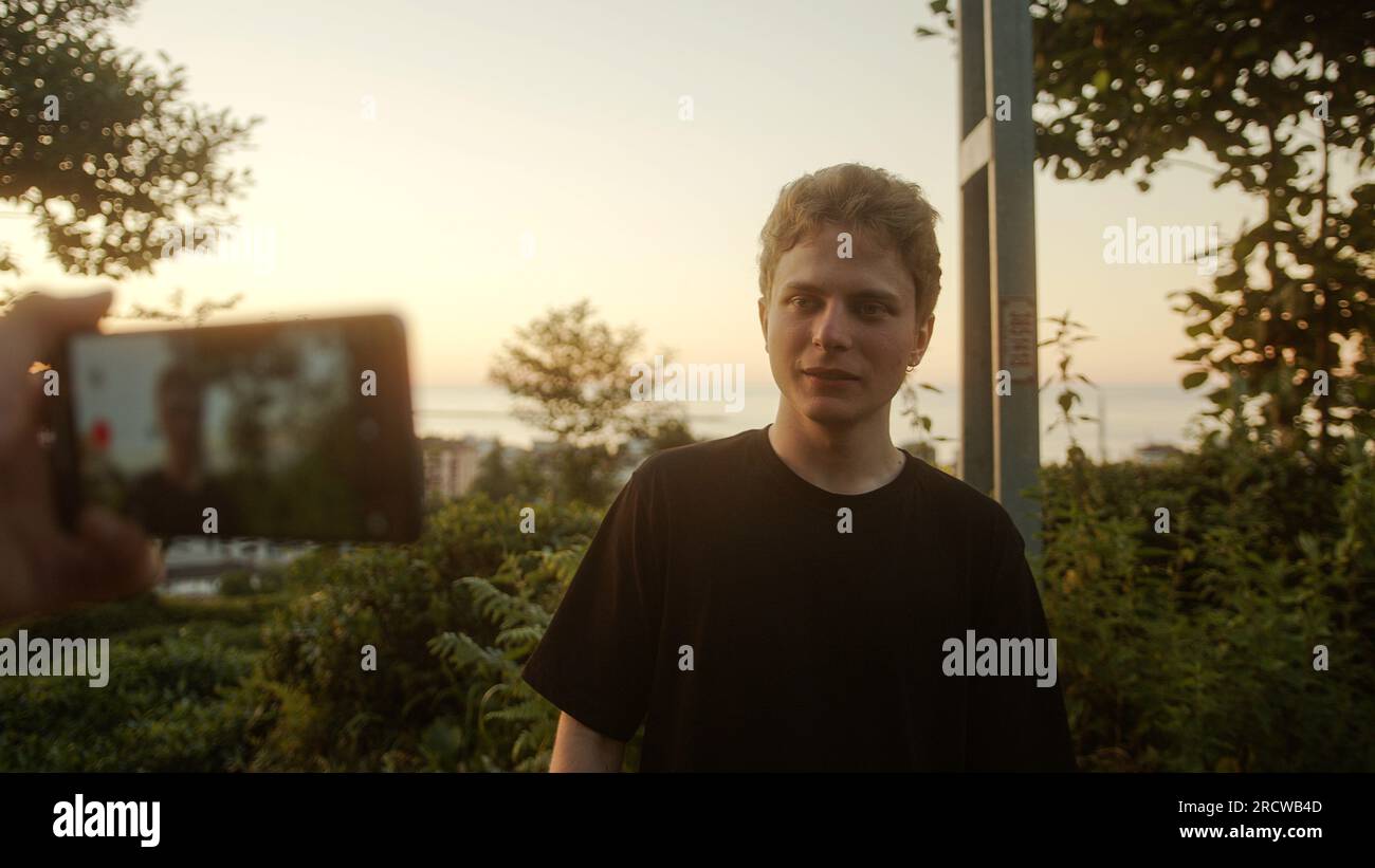 Young Blond Influencer with Colored Eyes registrandosi all'aperto, fenomeno dei social media Foto Stock