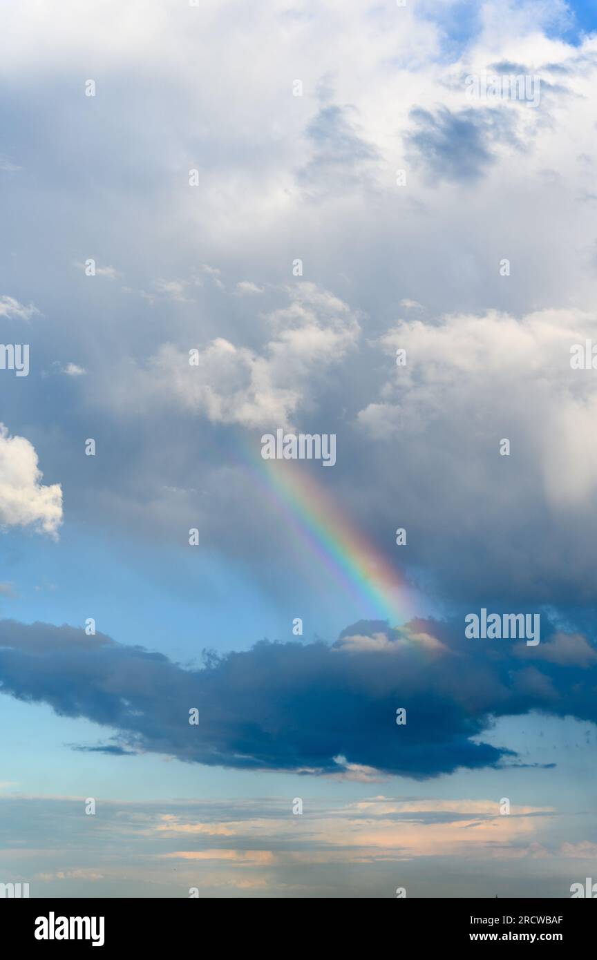 Incredibile arcobaleno luminoso sullo sfondo di un cielo tempestoso. Nuvole di tuoni, cielo blu, arcobaleno dopo pioggia nel cielo. Foto Stock