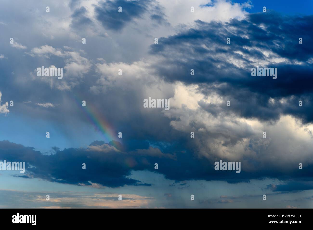 Incredibile arcobaleno luminoso sullo sfondo di un cielo tempestoso. Nuvole di tuoni, cielo blu, arcobaleno dopo pioggia nel cielo. Foto Stock