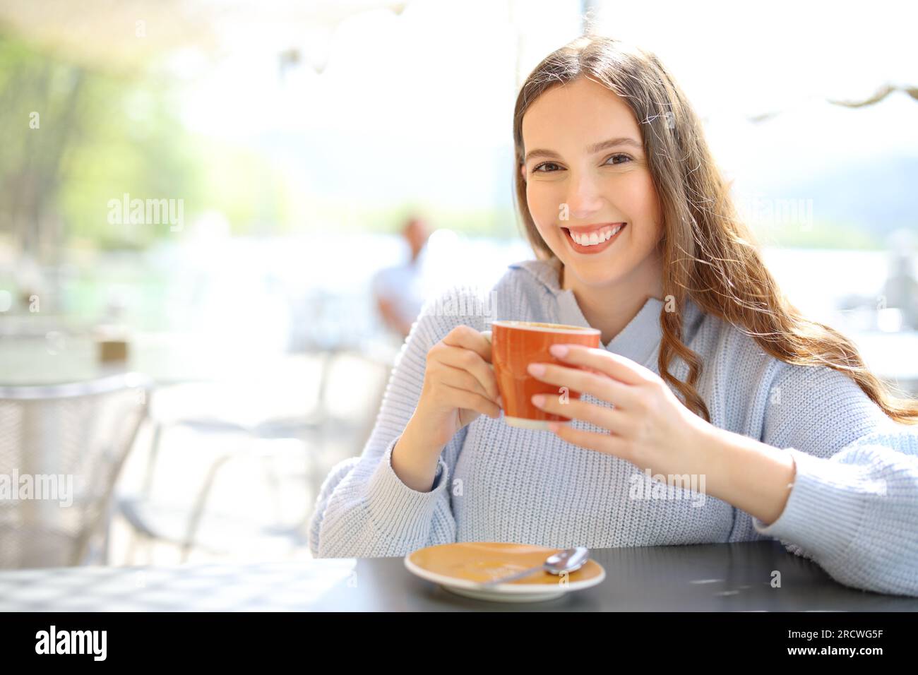 Cliente soddisfatto del ristorante che tiene una tazza di caffè guardando la macchina fotografica in terrazza Foto Stock