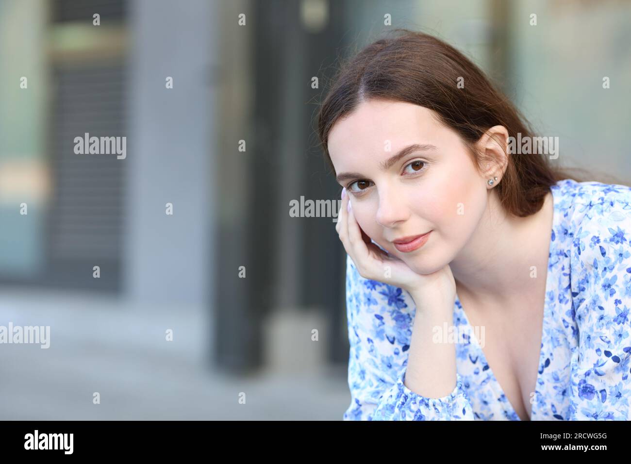 Una donna sicura di sé guarda la telecamera seduta in strada Foto Stock