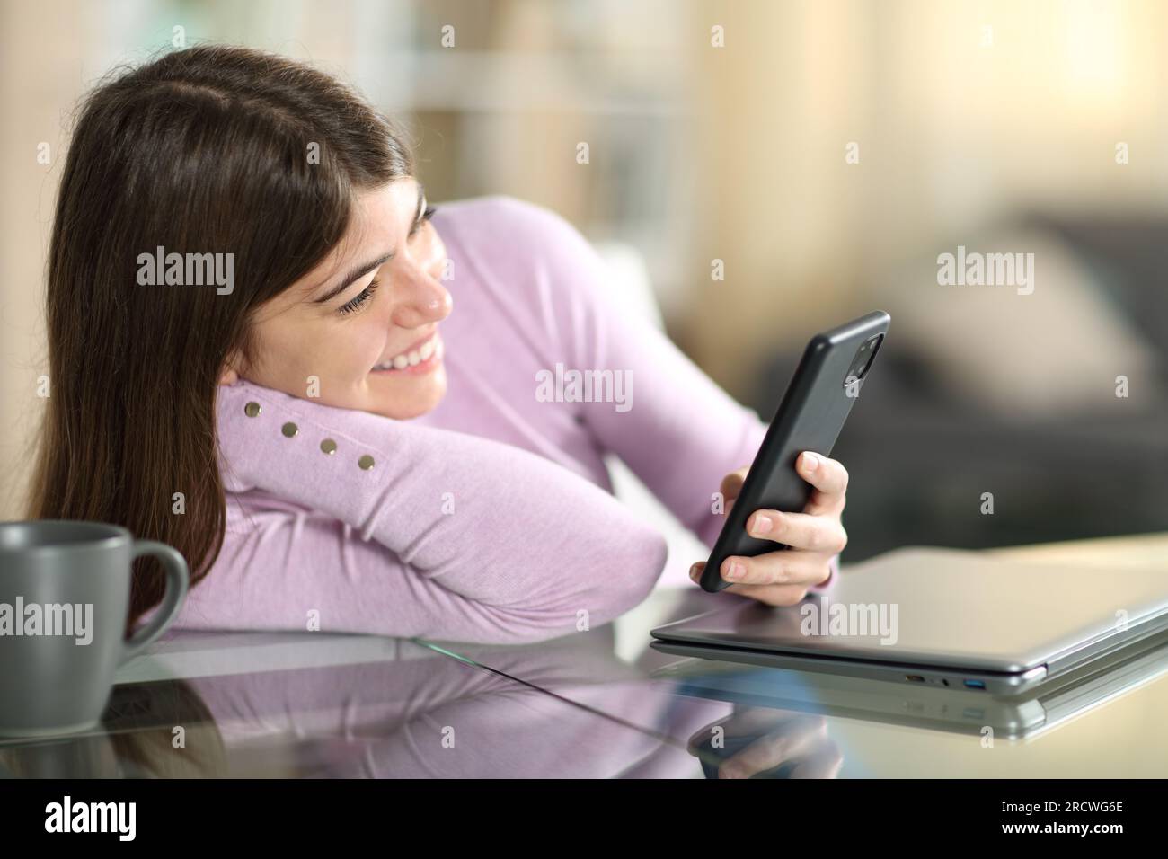 Un adolescente felice che guarda contenuti sul telefono seduto a casa Foto Stock