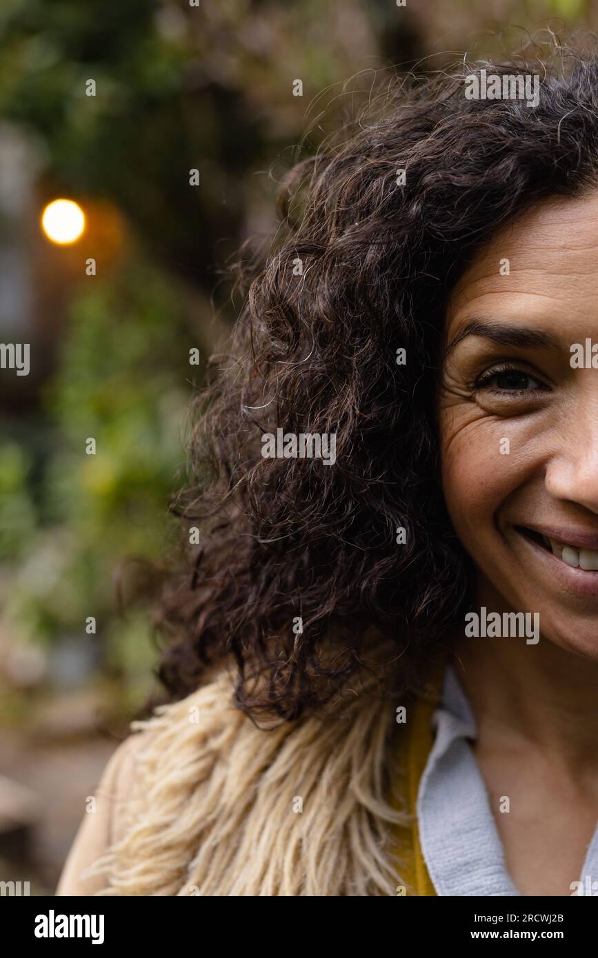 Ritratto di donna felice birazziale con capelli ricci scuri sorridenti in giardino Foto Stock