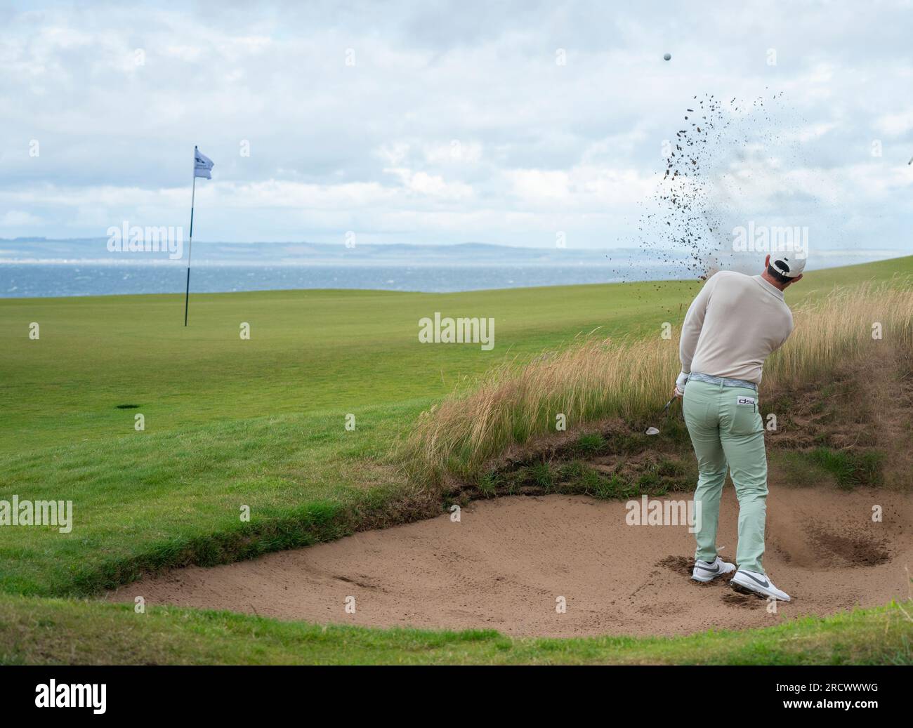 Rory McIlroy gioca fuori dal bunker sulla dodicesima buca durante il Genesis Scottish Open 2023 al Renaissance Club di North Berwick, in Scozia Foto Stock