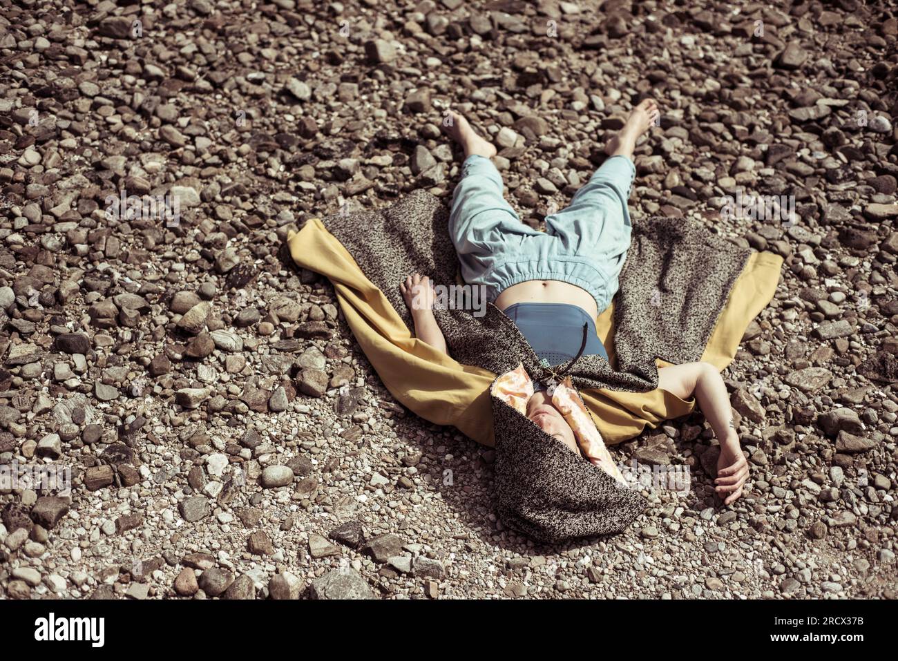 la ragazza in mantello si stende sulle pietre al sole Foto Stock