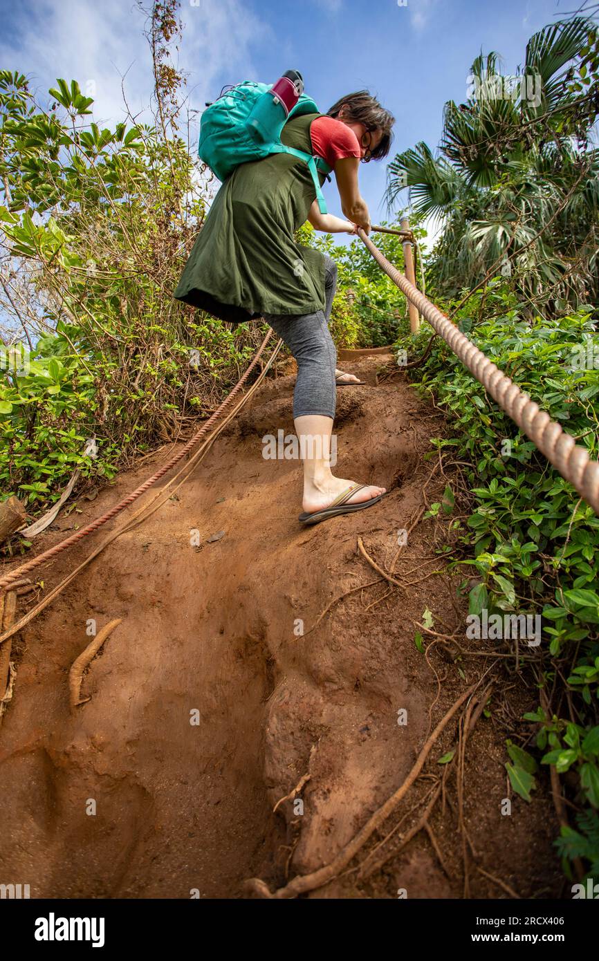 Utilizzando la corda per scendere lungo un sentiero ripido e scivoloso, Kauai Foto Stock
