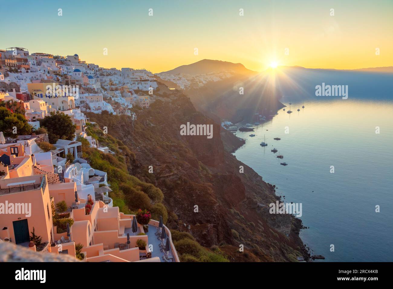 Santorini, Grecia. Alba sulla famosa isola di Santorini, vista della città di Oia. Il sole sorge e illumina la tradizionale architettura greca Foto Stock