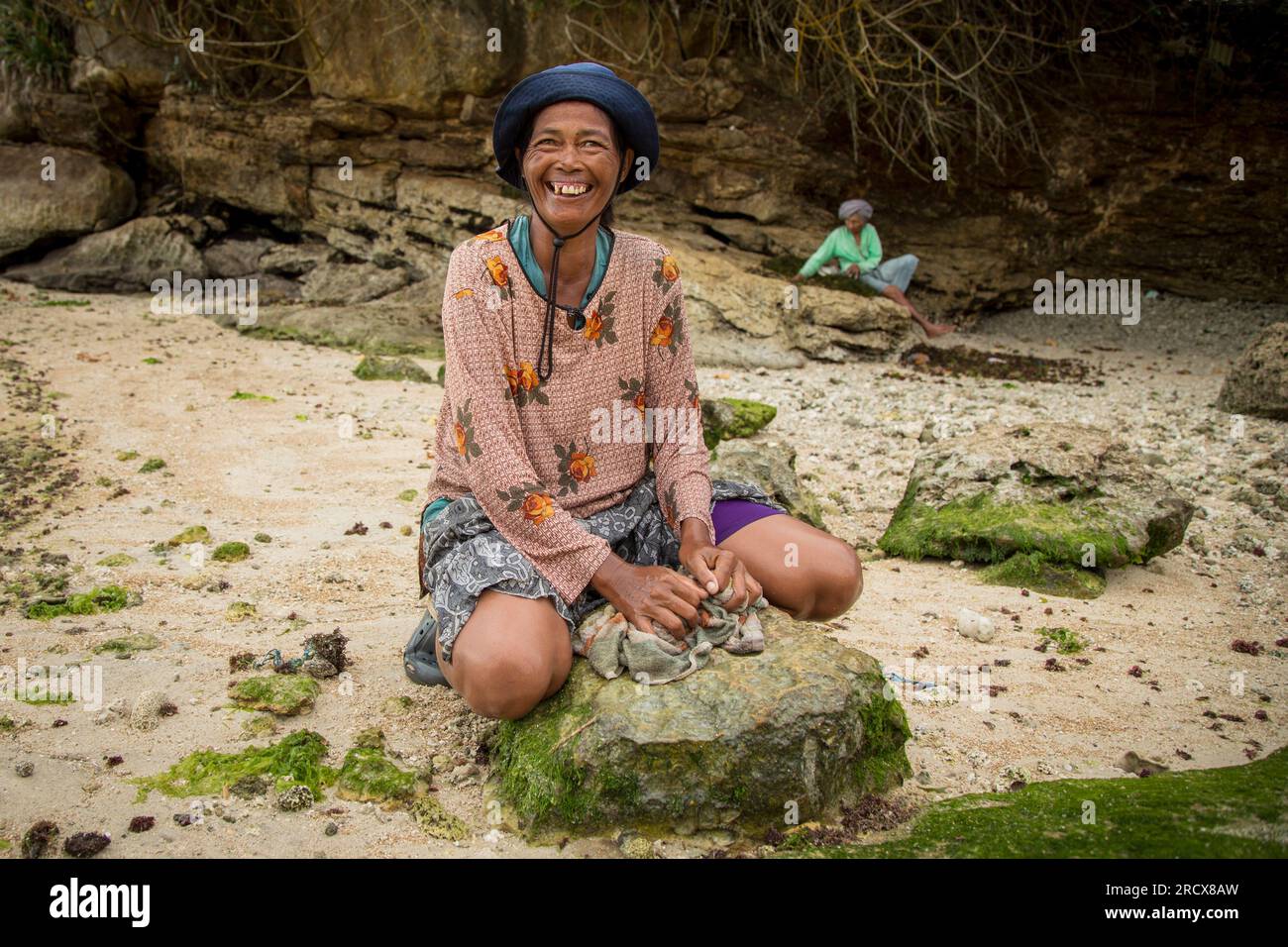 Donna sorridente che risciacqua un panno su una roccia Foto Stock