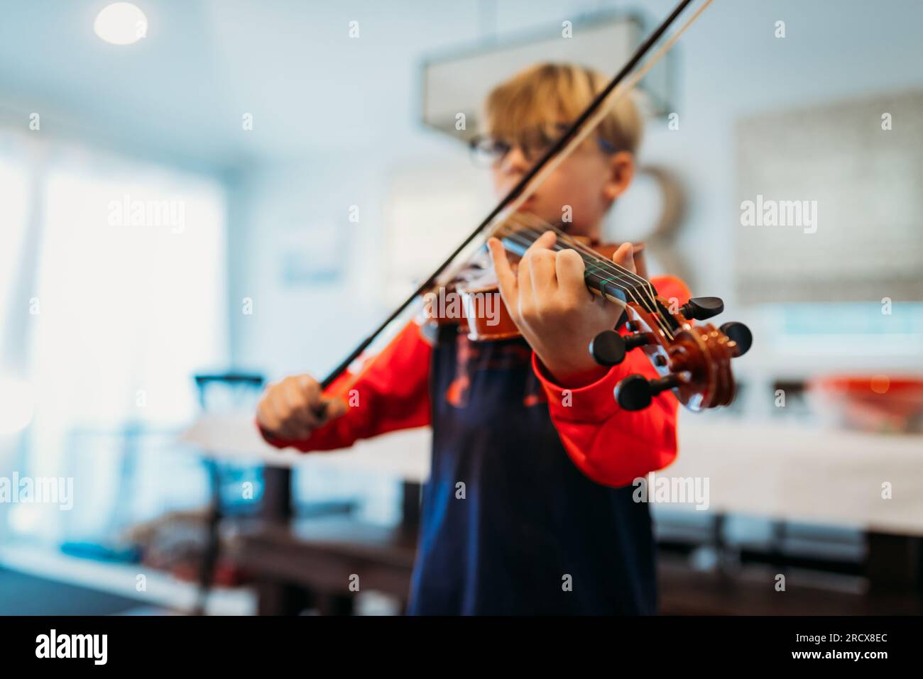 Ragazzo che gioca a viola in casa con le mani a fuoco Foto Stock