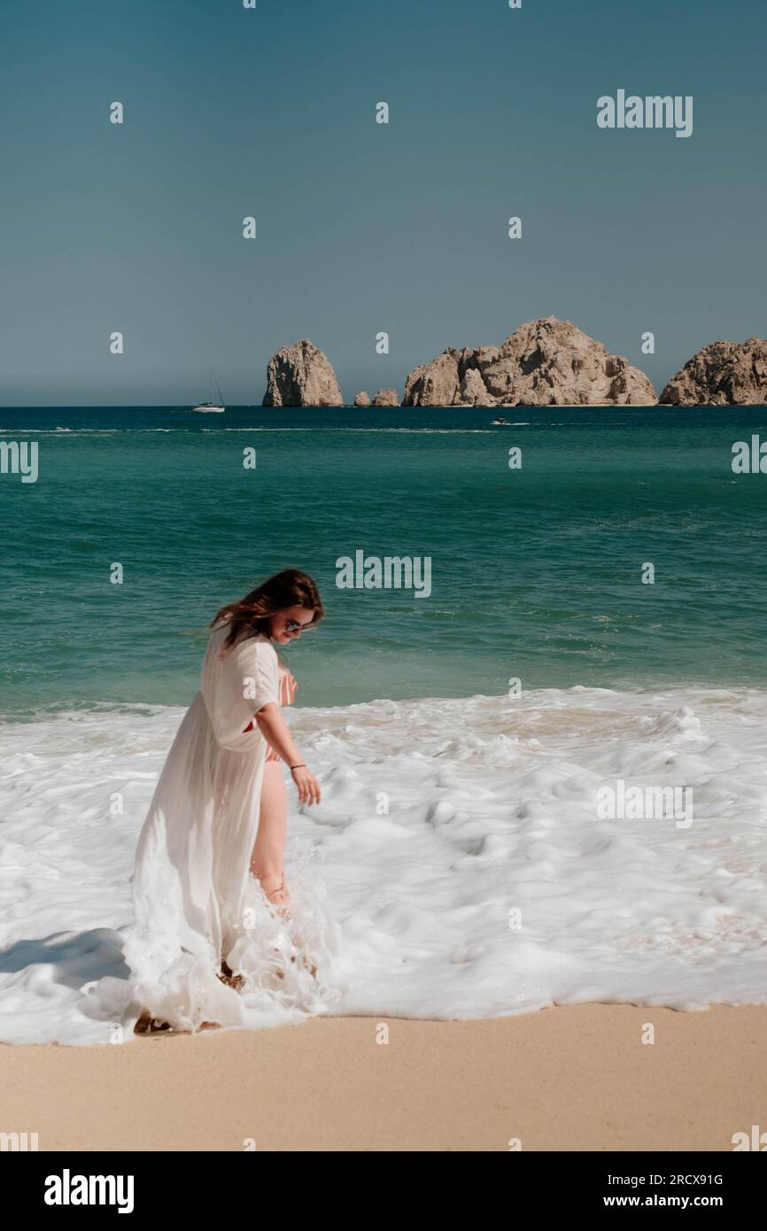 Una bruna donna bianca che si nasconde tra le onde di Cabo San Lucas Foto Stock