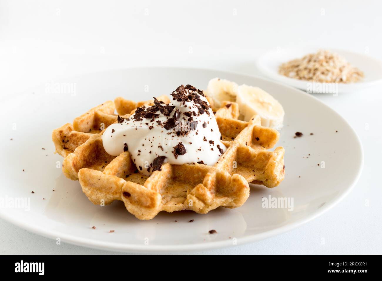 Deliziosi waffle di farinata d'avena fatti in casa con cremoso yogurt naturale, miele, banana e cioccolato tritato Foto Stock