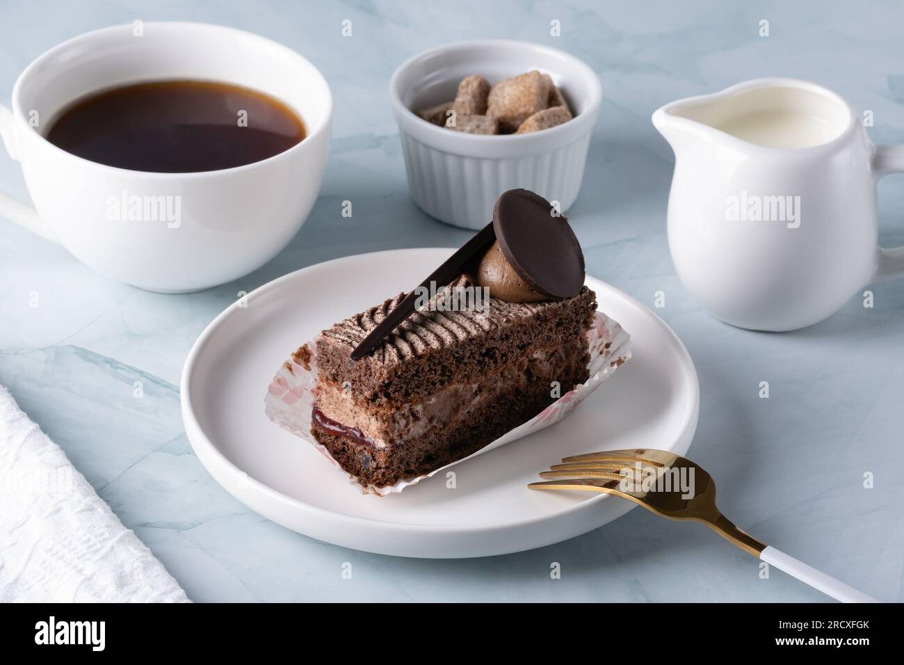 Deliziosa torta al cioccolato sul piatto e caffè sul tavolo leggero Foto Stock