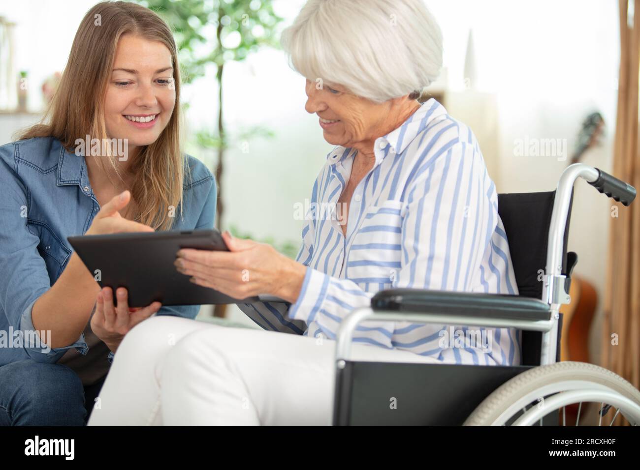 donna seduta con la madre anziana che usa un tablet Foto Stock