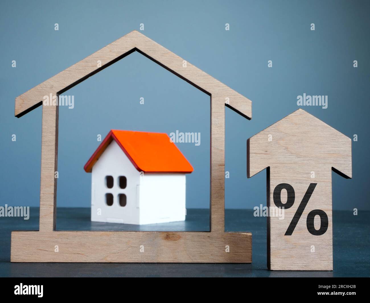 Modello di casa, freccia e segno di percentuale come concetto di tassi ipotecari. Foto Stock
