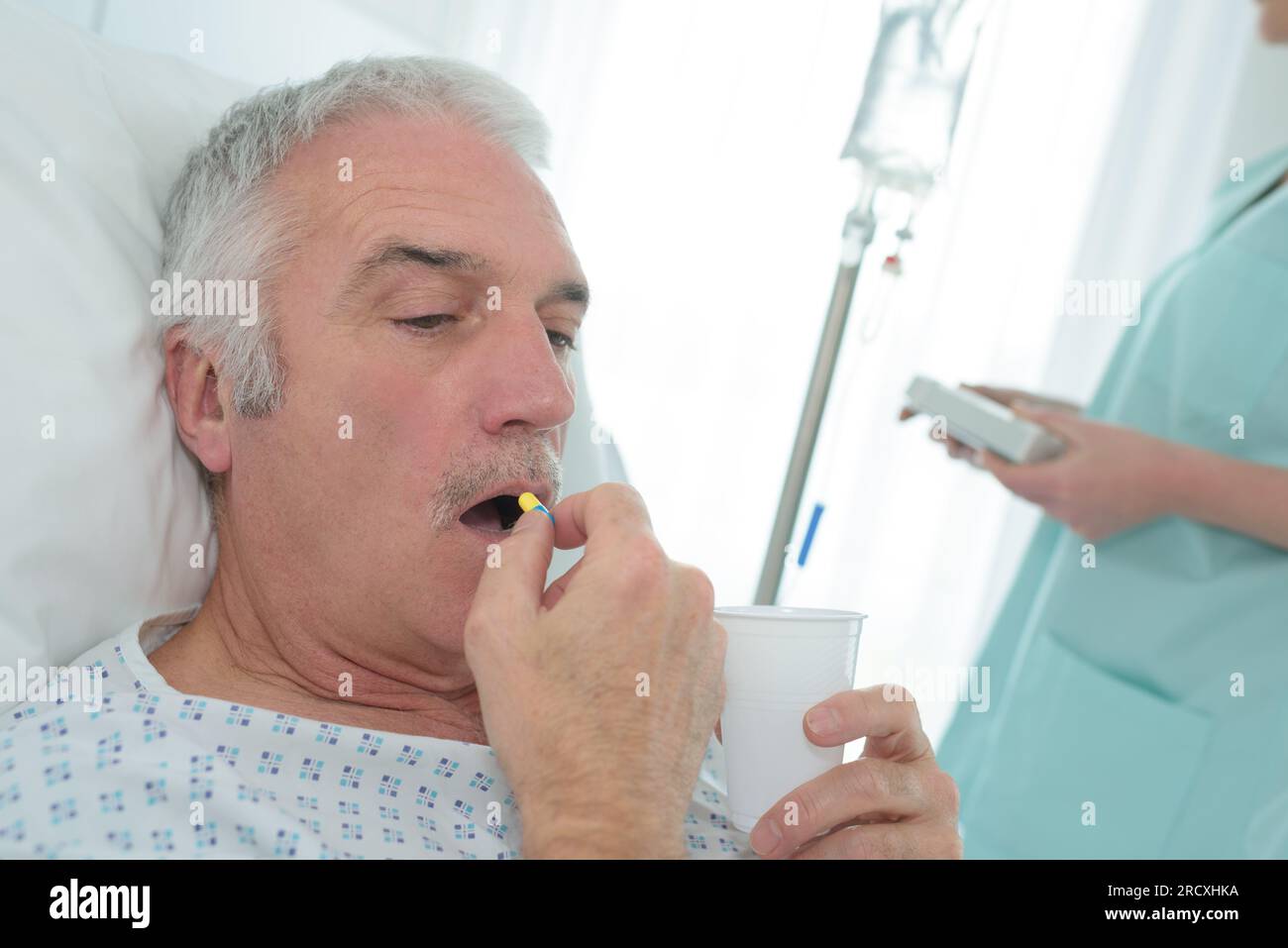 un anziano in ospedale che prende una pillola Foto Stock