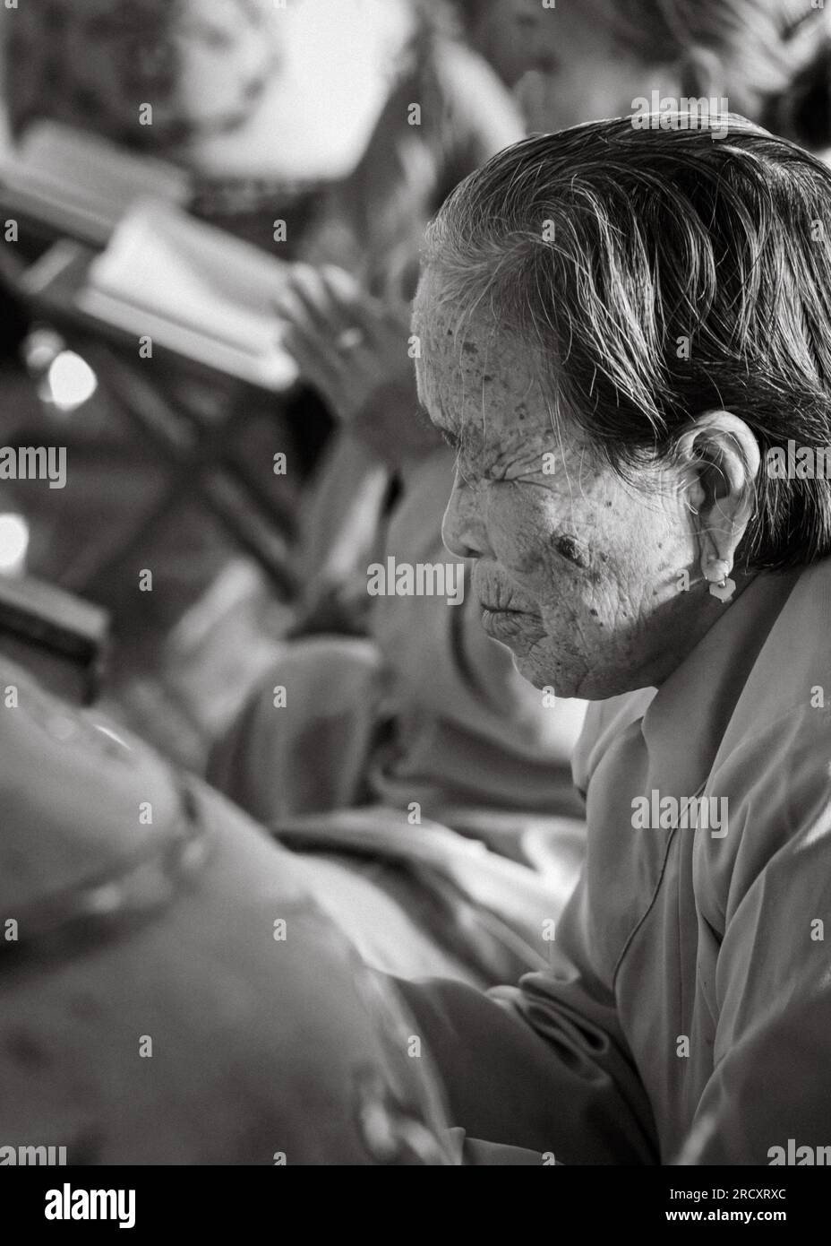 Una donna anziana che indossa orecchini di giada adora la pagoda buddista Ling Ung Bai Buc a Son tra, Danang, Vietnam. Foto Stock