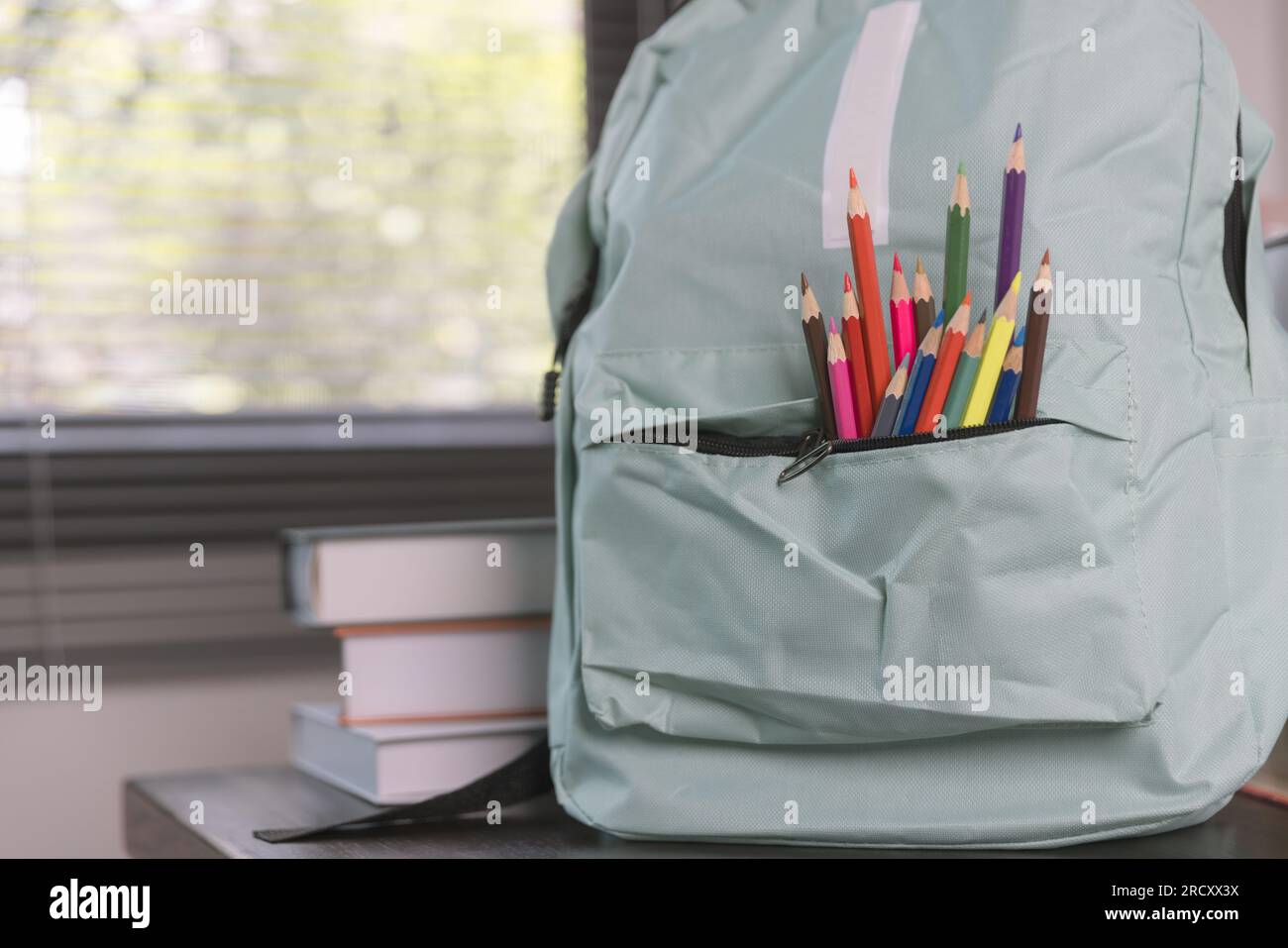 Forniture scolastiche su un tavolo di legno in interni caldi, libri scolastici sul tavolo, concetto educativo. Foto Stock